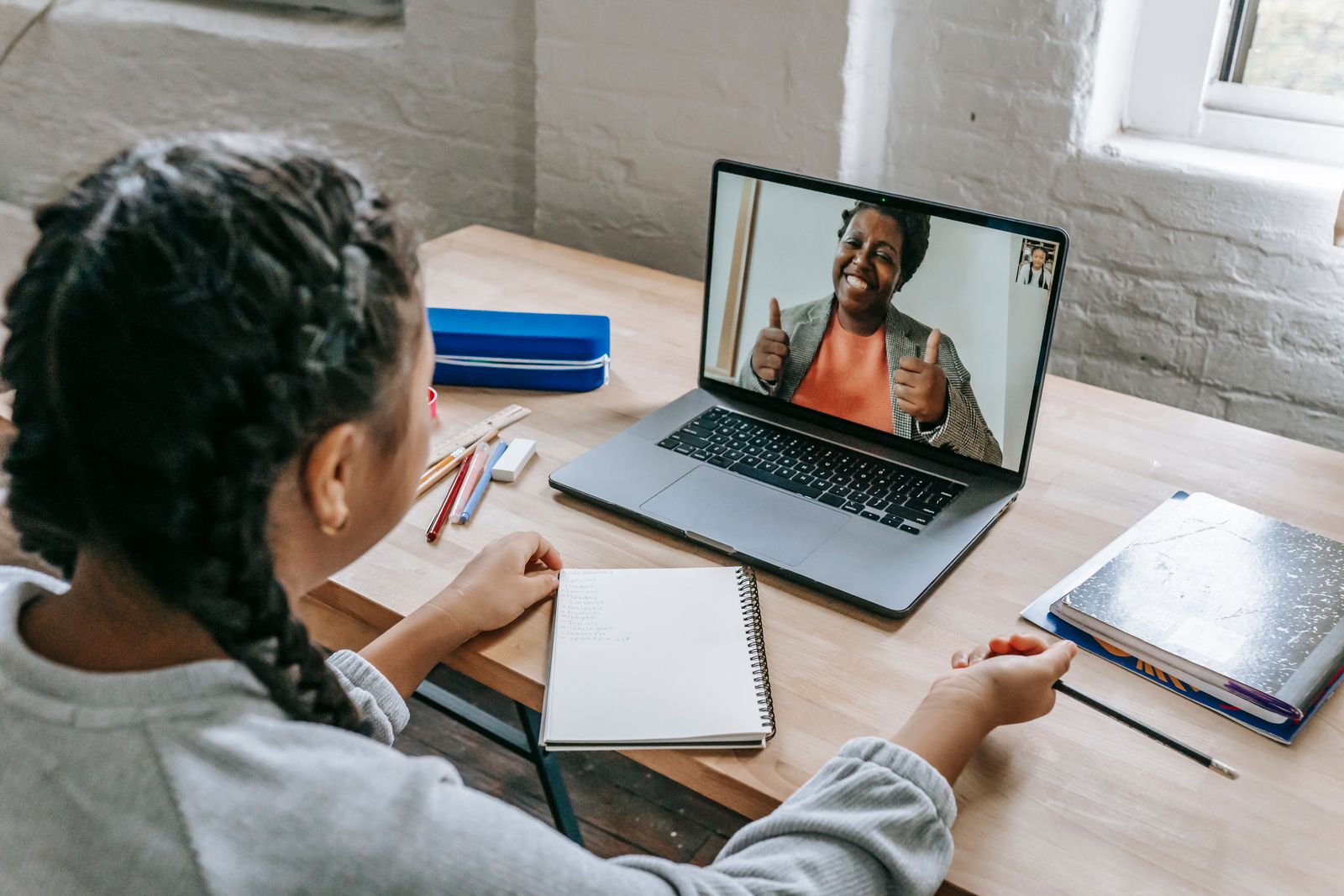 Estudante conversa com uma educadora por videochamada em um notebook.